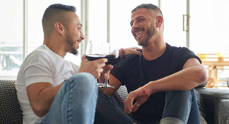 same-sex couple on sofa smiling at one another